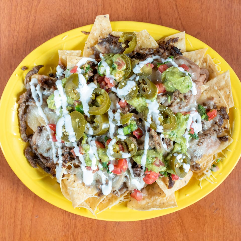 Loaded nachos with steak, melted cheese, guacamole, pico de gallo, sour cream, and jalapeños.